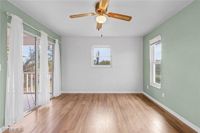 empty room with baseboards, ceiling fan, wood finished floors, and a healthy amount of sunlight