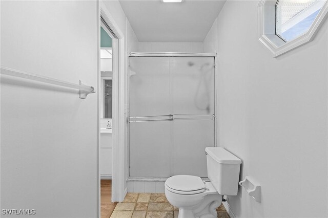 bathroom featuring toilet and a shower with door