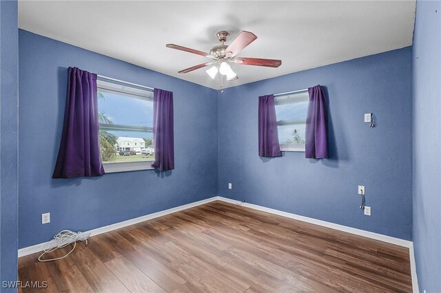 spare room featuring a ceiling fan, baseboards, and wood finished floors