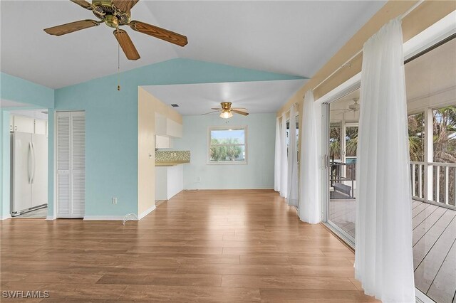 unfurnished living room with ceiling fan, vaulted ceiling, and wood finished floors