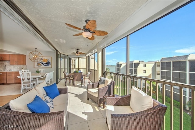 sunroom / solarium featuring ceiling fan with notable chandelier