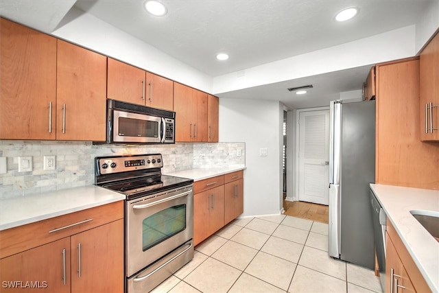 kitchen with light tile patterned floors, backsplash, and appliances with stainless steel finishes