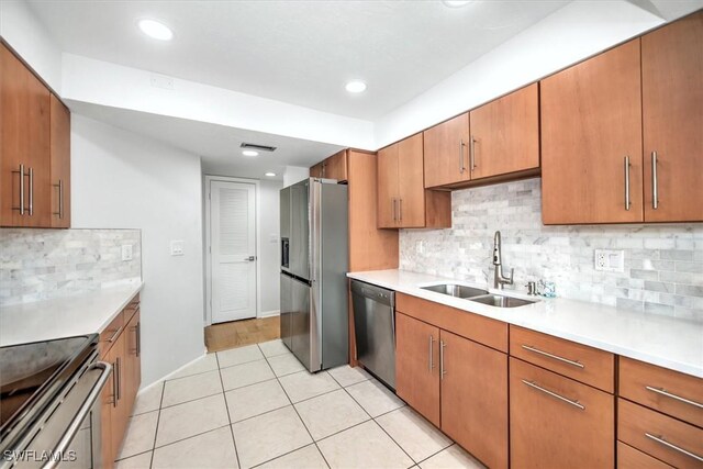 kitchen featuring tasteful backsplash, sink, light tile patterned floors, and appliances with stainless steel finishes