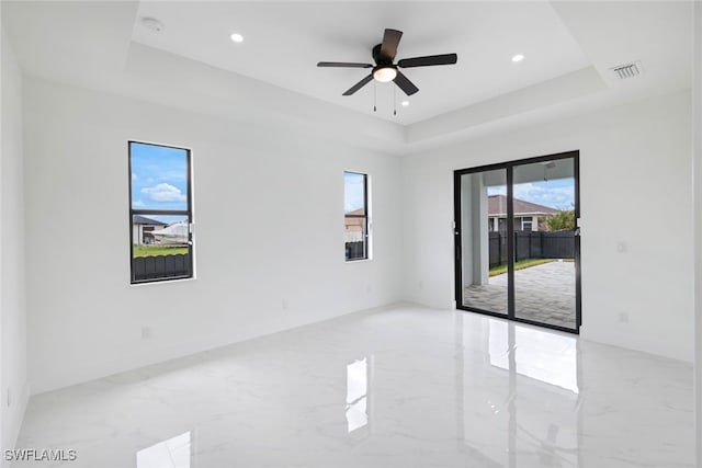 spare room featuring ceiling fan and a raised ceiling