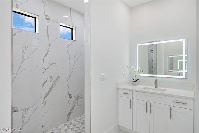 bathroom featuring tiled shower and vanity