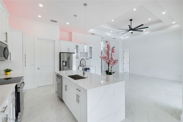 kitchen featuring stainless steel appliances, sink, decorative light fixtures, white cabinetry, and an island with sink