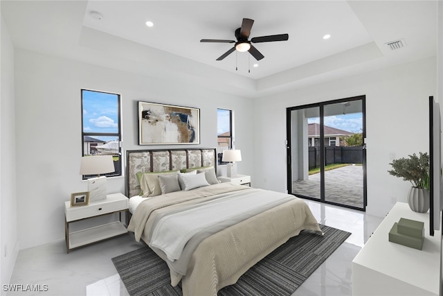 bedroom featuring ceiling fan, access to outside, and a tray ceiling