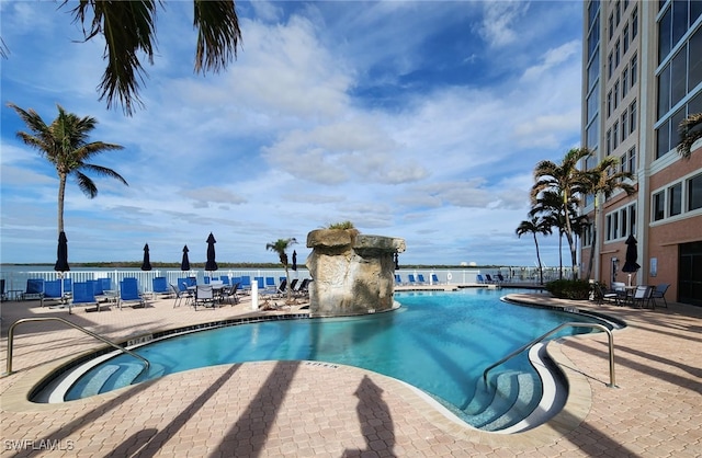 view of swimming pool featuring a water view and a patio area