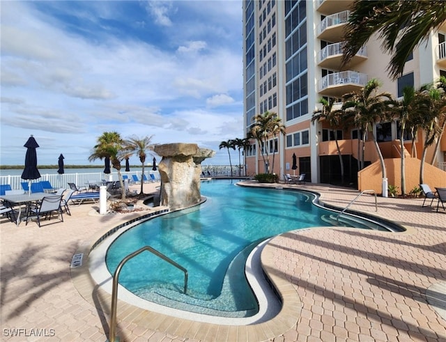 view of pool with a patio and a water view