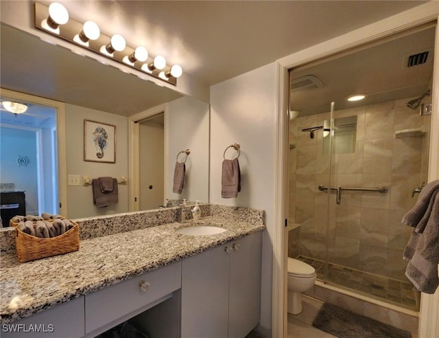 bathroom featuring tile patterned flooring, vanity, an enclosed shower, and toilet