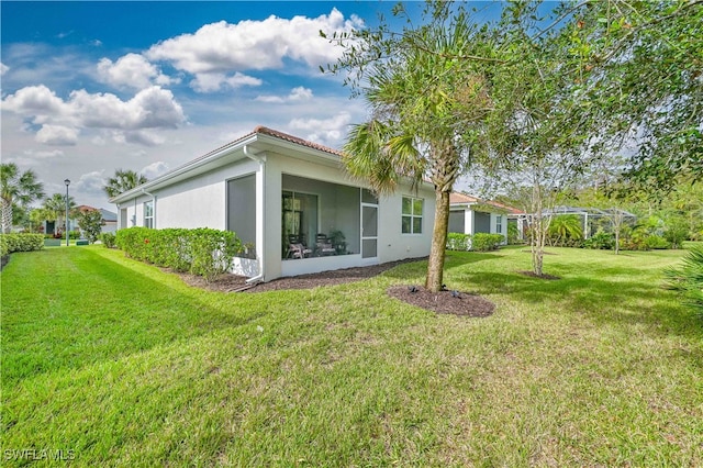 rear view of property featuring a yard and a sunroom