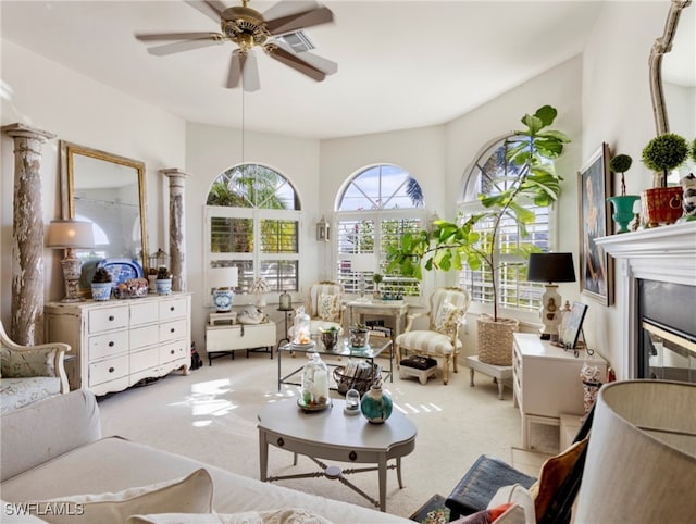 living room with ceiling fan, ornate columns, and light carpet