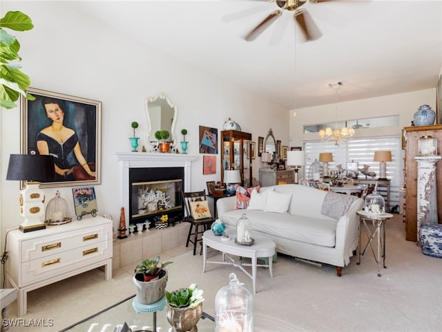 carpeted living room with a fireplace and ceiling fan with notable chandelier