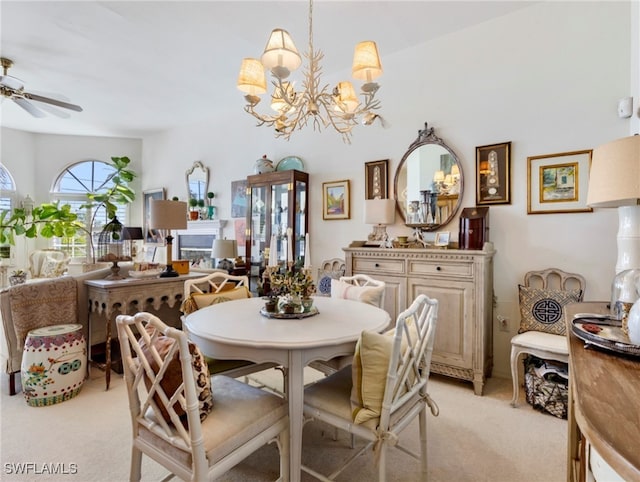 dining space featuring ceiling fan with notable chandelier, light colored carpet, and lofted ceiling