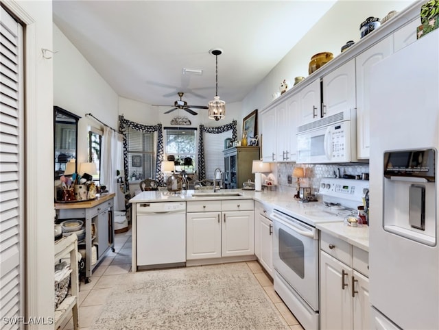 kitchen featuring pendant lighting, white appliances, sink, light tile patterned floors, and kitchen peninsula