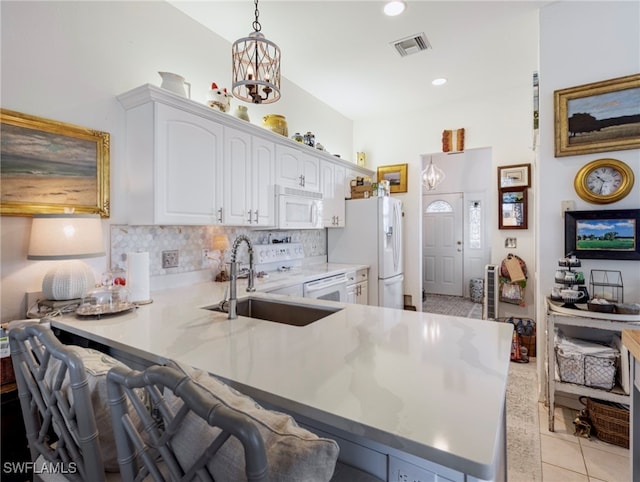 kitchen featuring white appliances, sink, hanging light fixtures, white cabinetry, and kitchen peninsula