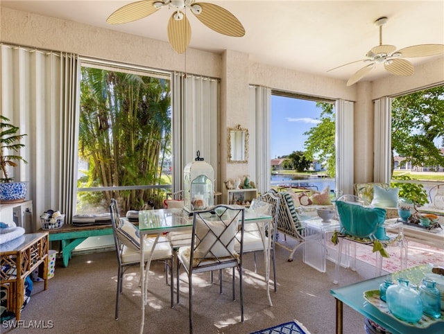 sunroom / solarium featuring ceiling fan and a water view