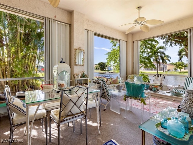 sunroom featuring ceiling fan and a water view