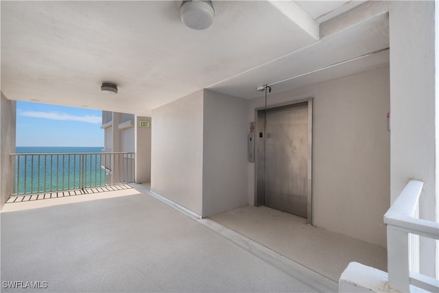 interior space featuring a water view, elevator, and a balcony