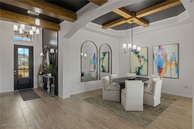 dining space featuring a notable chandelier, beam ceiling, and light hardwood / wood-style flooring