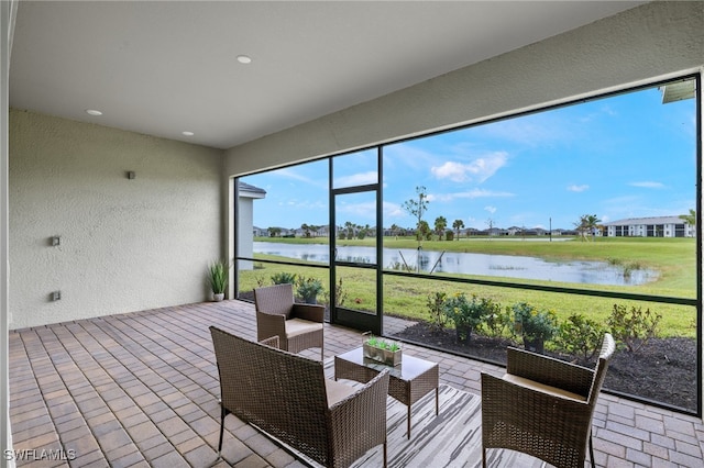 sunroom featuring a water view