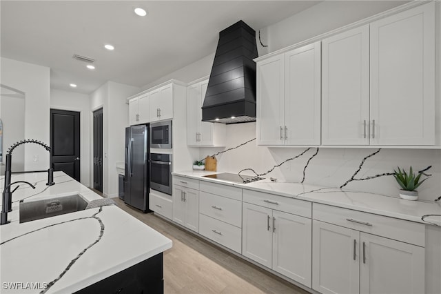 kitchen with white cabinets, light wood-type flooring, custom range hood, and stainless steel appliances