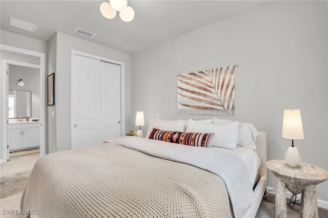 bedroom featuring carpet flooring, a closet, ensuite bathroom, and sink