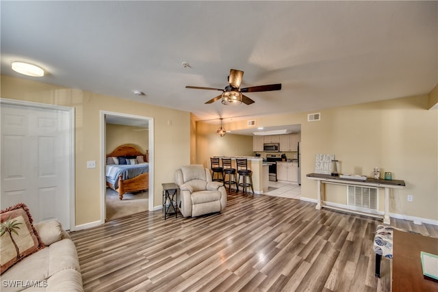 living room with ceiling fan and light hardwood / wood-style flooring