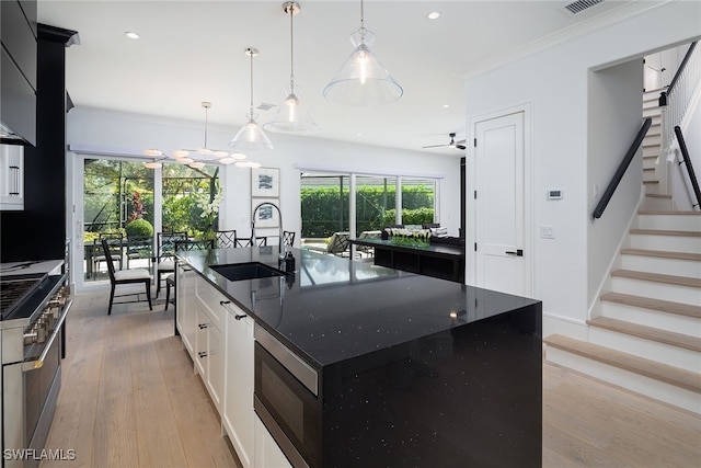 kitchen featuring ceiling fan, a center island with sink, decorative light fixtures, and sink