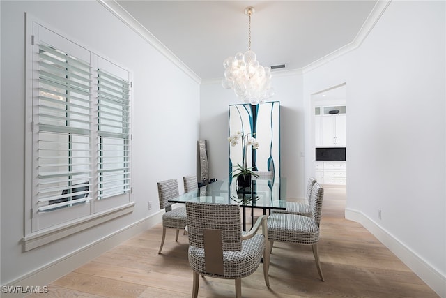 dining room featuring a notable chandelier, light hardwood / wood-style floors, and crown molding