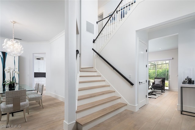 stairs featuring crown molding, a chandelier, and hardwood / wood-style flooring