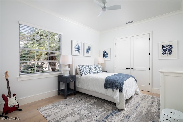 bedroom with wood-type flooring, a closet, ceiling fan, and ornamental molding