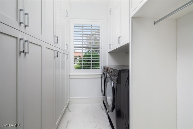 washroom with washing machine and clothes dryer and cabinets