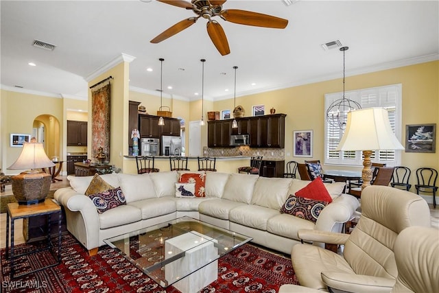 living room featuring ornamental molding and ceiling fan with notable chandelier