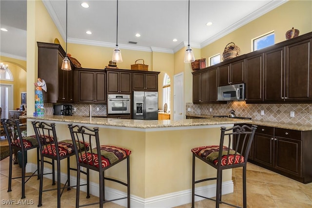 kitchen featuring stainless steel appliances, light stone countertops, hanging light fixtures, and a breakfast bar area