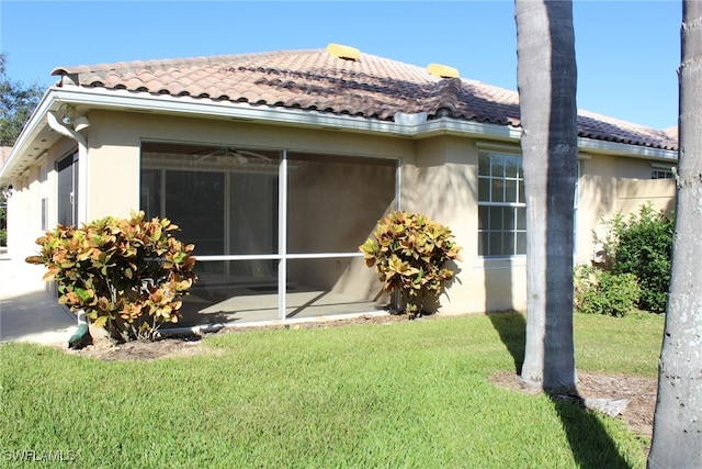 view of side of home featuring a sunroom and a yard