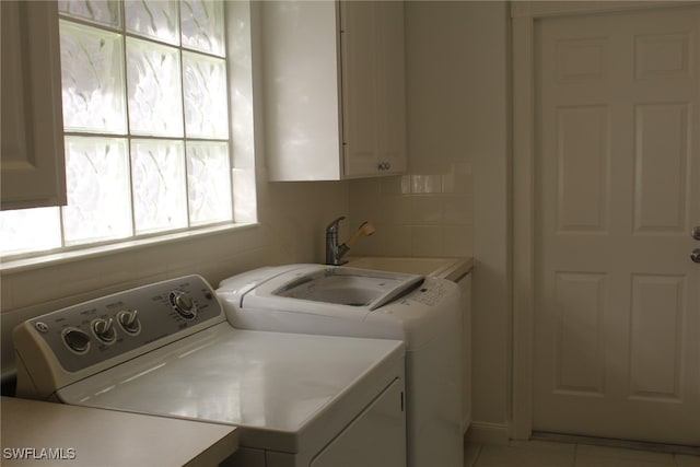 laundry room featuring washing machine and clothes dryer, sink, light tile patterned floors, and cabinets