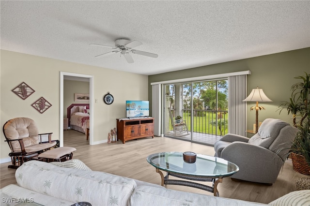 living room with a textured ceiling, light hardwood / wood-style floors, and ceiling fan