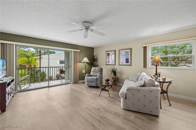 living area with a textured ceiling, light wood-type flooring, and ceiling fan