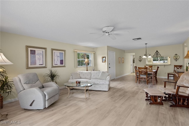 living room with a textured ceiling, light hardwood / wood-style floors, and ceiling fan with notable chandelier