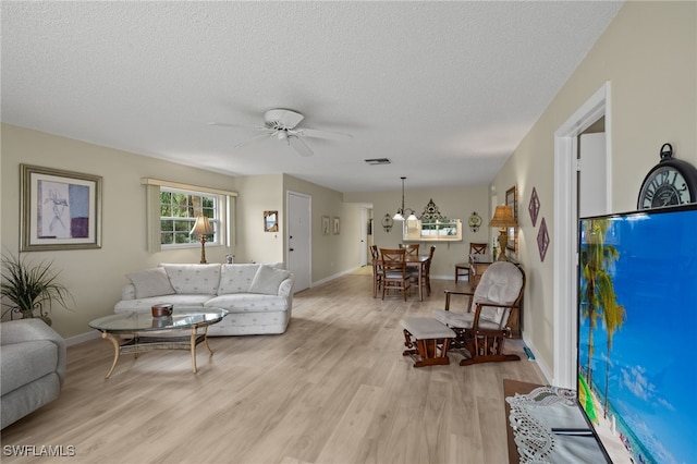 living room with a textured ceiling, light wood-type flooring, and ceiling fan