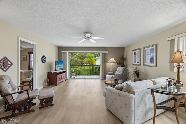 living room with a textured ceiling, light hardwood / wood-style flooring, and ceiling fan