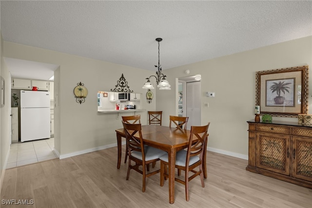 dining space featuring a chandelier, a textured ceiling, and light hardwood / wood-style flooring