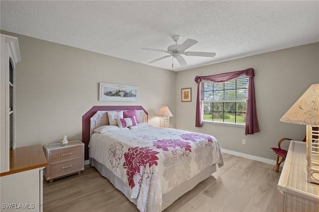 bedroom with ceiling fan, light hardwood / wood-style floors, and a textured ceiling