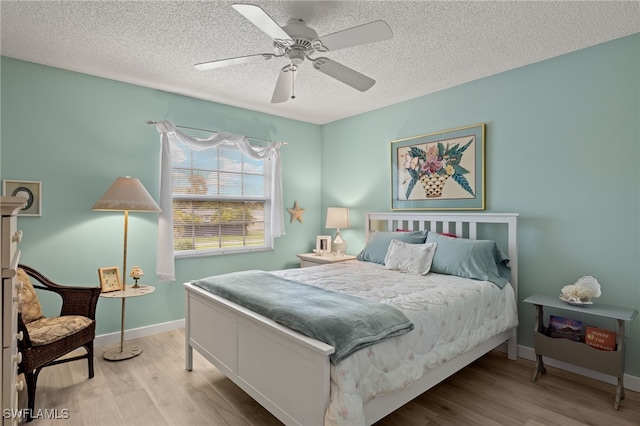 bedroom with ceiling fan, light hardwood / wood-style flooring, and a textured ceiling