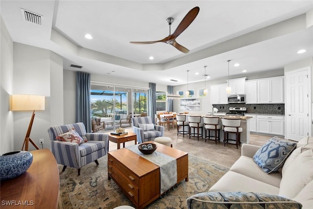 living room featuring a raised ceiling and ceiling fan