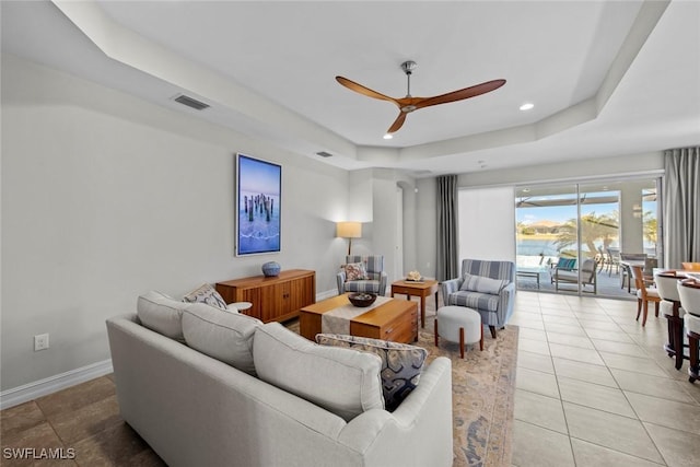 tiled living room featuring a tray ceiling and ceiling fan