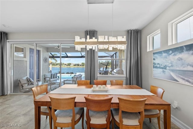 dining area with ceiling fan and a water view