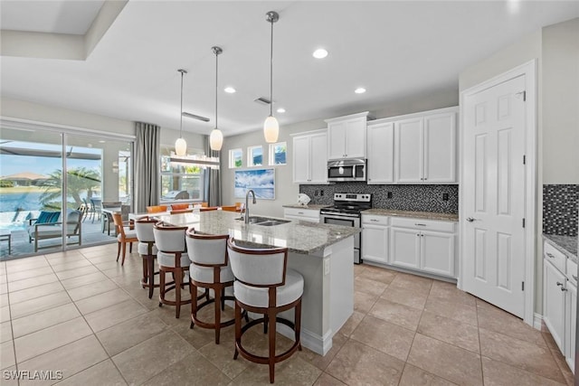 kitchen featuring white cabinets, sink, appliances with stainless steel finishes, and an island with sink