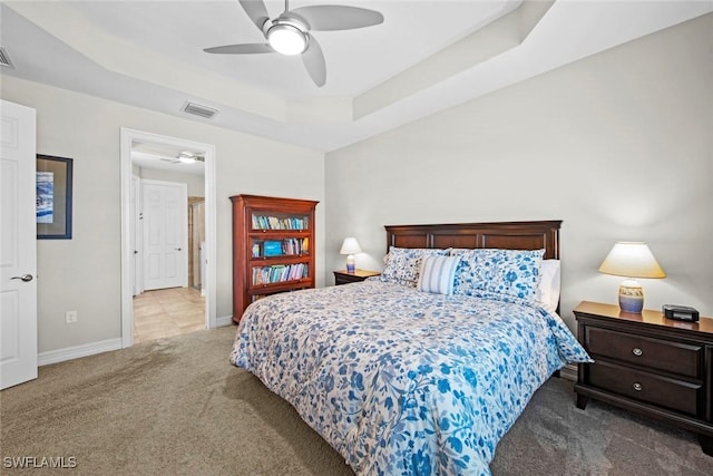 carpeted bedroom with a tray ceiling and ceiling fan